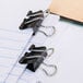 A black Universal mini binder clip on a piece of paper.