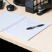 A black Universal 1 subject notebook on a desk with a pen.
