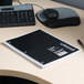 A black Universal wirebound notebook on a desk next to a keyboard.