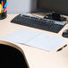 A black Universal spiral bound notebook on a desk with a computer.