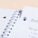 A black Universal spiral notebook with wide ruled paper and writing on the cover.