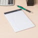 A Universal white legal writing pad on a table with a pen.