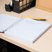 A Universal 5 subject spiral notebook on a desk with pencils.
