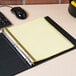 A Universal plastic-coated numerical tab divider in a binder on a desk with yellow paper.