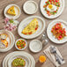 An Acopa ivory stoneware platter on a table with food plates.