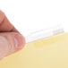 A person's finger inserting a white strip into a clear plastic divider tab.