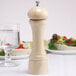 A close-up of a wooden Chef Specialties Windsor pepper mill on a table.