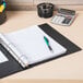 An Avery black economy view binder on a desk with a pen and calculator.