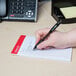 A hand using a black and white pen to write on a Universal narrow ruled writing pad.