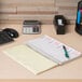 A Universal wirebound message book on a desk with a calculator, pen, and a calculator.
