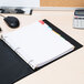 A Universal multi-color binder divider with a white page in a binder on a desk.