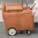 A woman pushing a Cambro Coffee Beige Mobile Ice Bin on a counter.