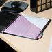 A black Universal Deluxe non-stick view binder on a desk with purple grid paper inside.