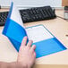 A person's hand holding a blue Avery 2-pocket folder.