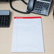 A white Universal Legal Rule Writing Pad on a desk with a phone and a computer.