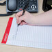 A hand using a pen to write on a Universal Legal Rule Writing Pad.