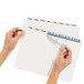 A hand holding a white piece of paper with a blue and white label using Avery Index Maker Extra-Wide Dividers.