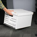 A person's hand holding a white Universal letter/legal storage box with a lift-off lid.