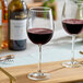 A clear wine glass filled with red wine, placed on a wooden surface.
