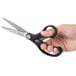 A hand holding Universal stainless steel scissors with black bent handles.