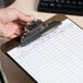 A person's hand holding a Universal Smoke High Capacity Plastic Clipboard with a metal clip.