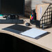 A black Universal Deluxe View Binder on a desk with a computer and other office supplies.