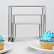 A stainless steel American Metalcraft riser set with cupcakes on plates.