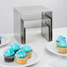 An American Metalcraft stainless steel riser set with cupcakes on them on a table in a bakery display.