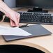 A hand holding a piece of paper on a Universal plastic landscape clipboard.