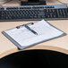 A Universal plastic landscape clipboard with a pen on it on a table with a keyboard.