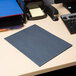 A dark blue Universal letter size paper folder on a blue desk with a computer.