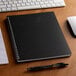 A Brownline DuraFlex planner open on a white surface with a notebook and pen.