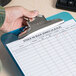 A hand holding a Universal blue plastic clipboard with a stack of papers on a counter.