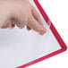 A hand holding a clear plastic sheet over a red corner of a report cover.