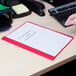 A hand using a computer keyboard to insert a white paper into a red Universal Office report cover.