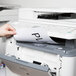 A hand putting a white Universal 8 1/2" x 11" label into a printer.