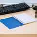 A blue National College Rule spiral notebook on a desk with a black keyboard.