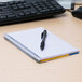 A blue National College Rule spiral notebook with pen on top.