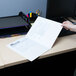 A hand placing a paper into a white Universal embossed pocket folder.