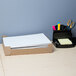 A white rectangular Universal letter size paper folder with a black border on a desk with a box of papers and stationery.