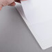 A hand with a finger holding a piece of paper in a Universal white deluxe view binder.