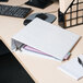 A white Universal Deluxe Non-Stick View Binder on a desk with a computer.