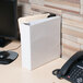 A white Universal Deluxe View Binder on a desk next to a phone.