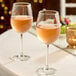A pair of clear wine glasses filled with rosé wine on a table.