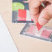 A hand putting a red Universal page flag into a plastic dispenser.