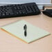 A brown National spiral steno notebook open on a desk with a pen on top.