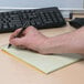 A hand holding a pen and writing in a National Brown Gregg Rule Steno Book.