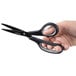 A hand holding Universal 8" carbon-coated industrial scissors with black and gray handles.