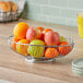 A Tablecraft oval chrome basket filled with apples and oranges on a table.