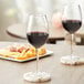 Two Acopa Select Blanc wine glasses on a table with cheese and crackers.